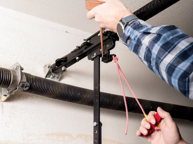 Technician inspecting a garage door spring with a tool